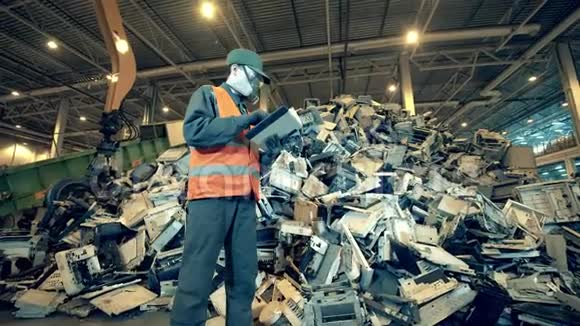 一堆破碎的设备在一个垃圾场与一个男工人垃圾废品垃圾回收中心视频的预览图