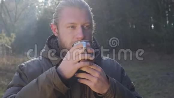 白种人留着灰色眼睛站在森林里喝着钢杯热茶的特写照片视频的预览图