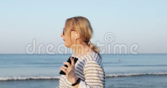 戴墨镜的金发老妇人正沿着海滨散步视频的预览图