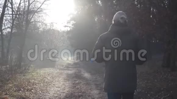 镜头跟随成年白种人男子在秋林路上行走男游客在户外旅行视频的预览图