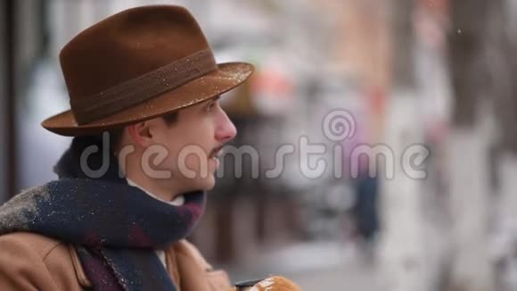 那家伙在街上喝热茶冬天男人在长凳上喝咖啡视频的预览图
