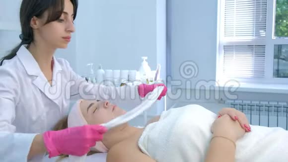 美容师用温毛巾擦拭女性面部保湿面膜视频的预览图