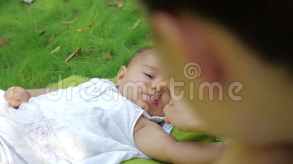 可爱的宝宝慢动作地对妈妈微笑闭上眼睛梦想的新生婴儿躺在户外草地上婴儿婴儿婴儿视频的预览图