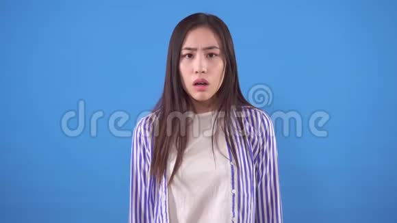 年轻的亚洲女人穿着衬衫在蓝色背景上做手掌视频的预览图