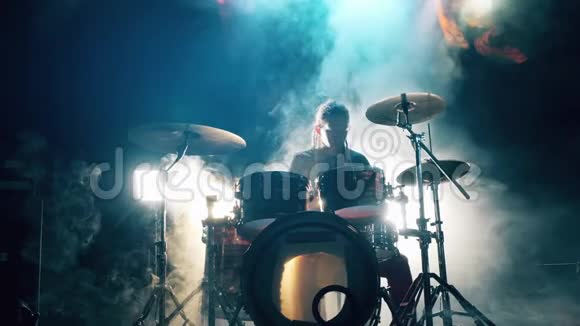 音乐家正在乌云密布的录音室里演奏架子鼓男鼓手在烟雾中打鼓视频的预览图