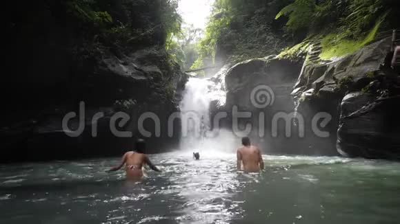 男性和女性游客在瀑布里洗澡享受淡水视频的预览图