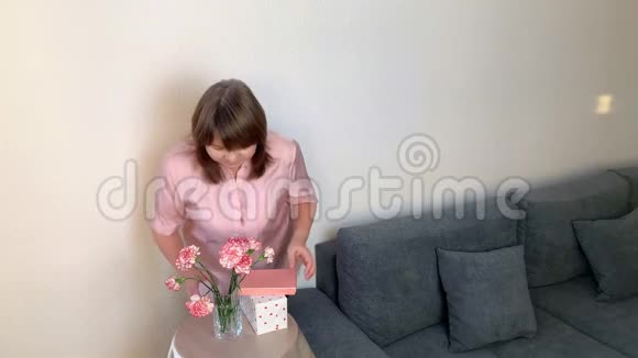 女人闻着一束粉红色的康乃馨微笑盒子里的礼物躺在圆桌上视频的预览图
