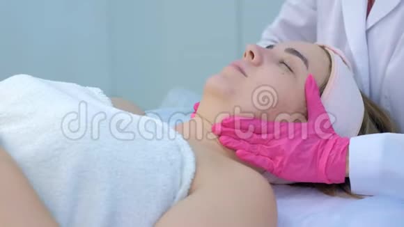 临床美容医生为年轻女性做颈部和面部按摩视频的预览图