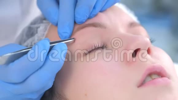 美容师用镊子把眉毛上的头发拔出来给女人面部特写视频的预览图