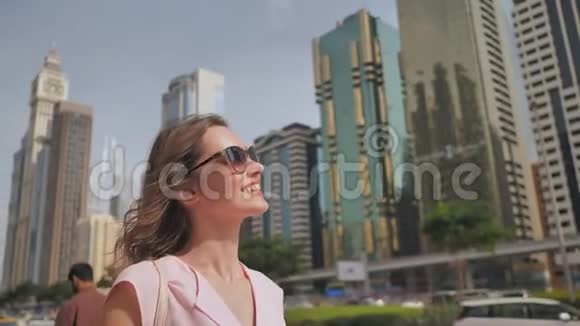 快乐的女孩在摩天大楼的背景下走在迪拜的中心视频的预览图