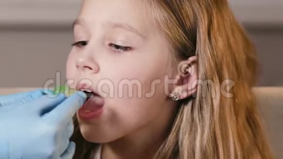 正牙医生在女孩的牙齿上放置一个特殊的盘子来对齐它们在童年时矫正牙齿视频的预览图