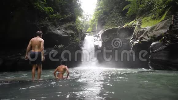 在热带雨林瀑布中的一对夫妇在夏天享受冰冷的泉水视频的预览图
