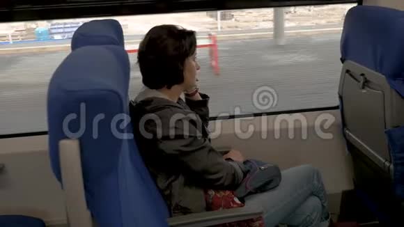 一个女人坐在火车上在电话旁的视野里说话视频的预览图