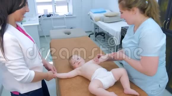 专业医生按摩师为躺在诊所沙发上的婴儿做按摩视频的预览图