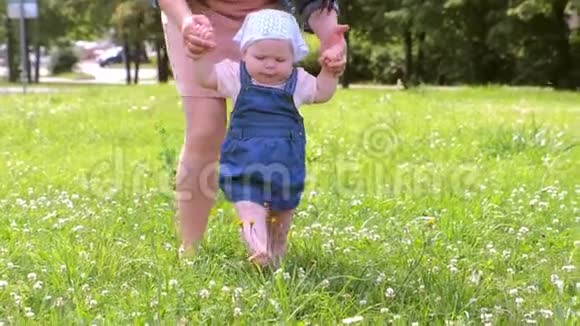 妈妈学习女婴走路第一步在公园里赤脚的腿视频的预览图