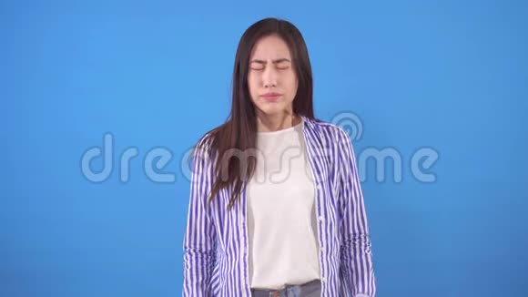 年轻的亚洲女人在蓝色背景下头痛视频的预览图
