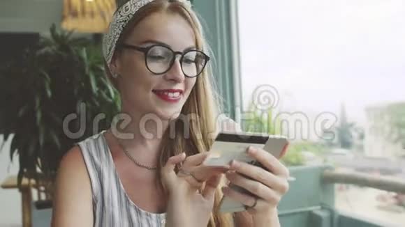 女人用信用卡和手机成功购买女性在咖啡馆网上购物视频的预览图