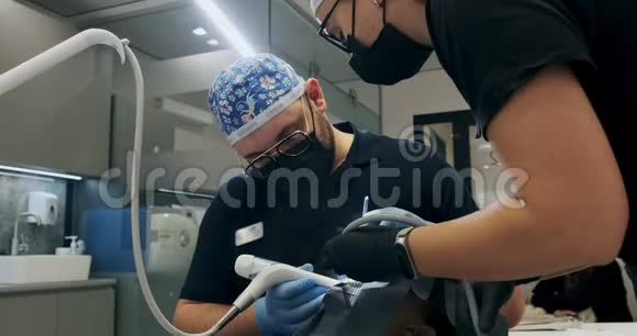 牙医在办公室工作两个牙医做空气流动牙齿清洁视频的预览图