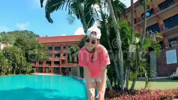 一个女人在游泳池附近跳舞在度假胜地玩得很开心视频的预览图