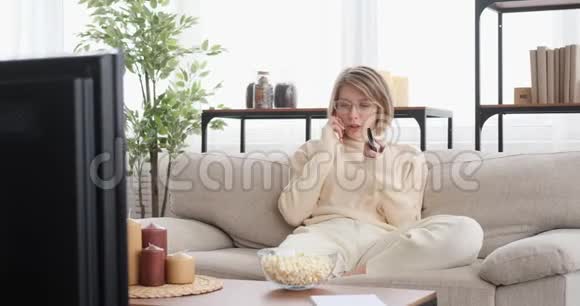 女人在家里用手机和看电视视频的预览图