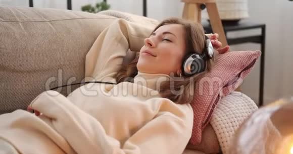 女人在沙发上放松和听音乐视频的预览图