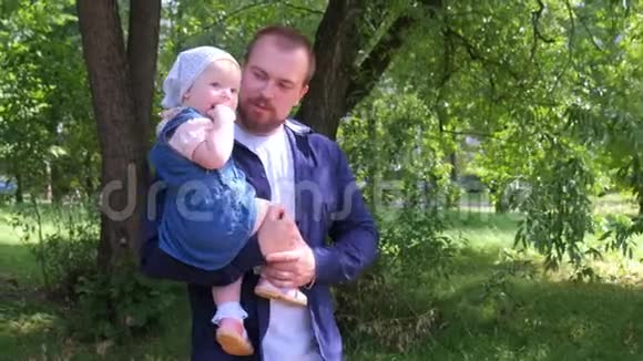 年轻爸爸抱着宝贝女儿在城市公园散步家庭肖像视频的预览图