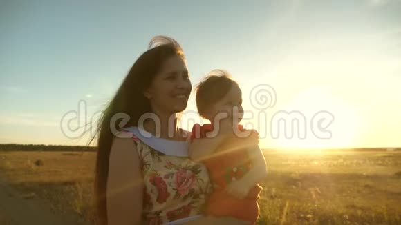 妈妈和小女儿正在麦田里沿着乡间的路走母亲和婴儿在大自然中行走快乐妈妈视频的预览图