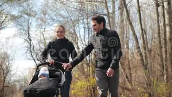 秋天在一个舒适的城市公园里一个快乐的年轻家庭轮滑的正面镜头慢动作丈夫和妻子视频的预览图