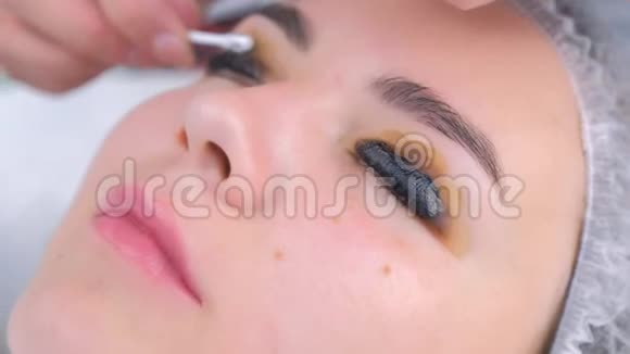 美容师在绘画过程中擦拭女孩睫毛的溶液视频的预览图