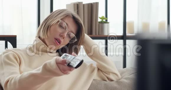 疲惫的女人在家看电视打哈欠视频的预览图