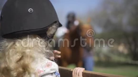 带防护头盔的小女孩等着骑马万向节运动视频的预览图