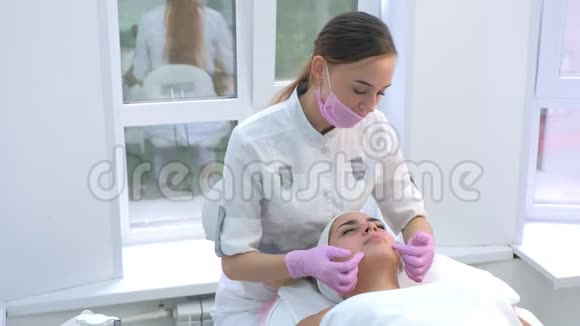 美容师在客户的女人脸和脖子上涂霜并按摩视频的预览图