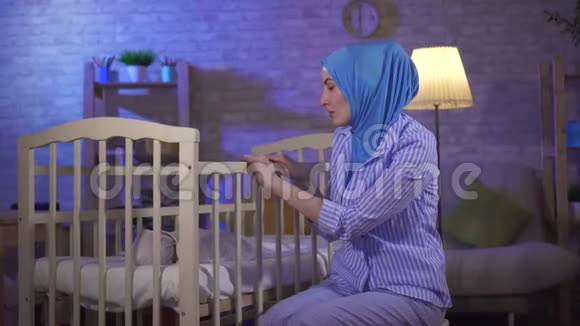 睡着了的肖像穆斯林年轻女子是一位婴儿床旁的母亲视频的预览图