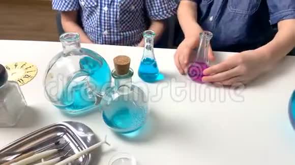 孩子们小学生把有色液体倒入玻璃瓶中从吸管和注射器中滴出早期概念视频的预览图