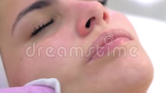 戴手套的美容师用棉垫清洁顾客女人的脸视频的预览图