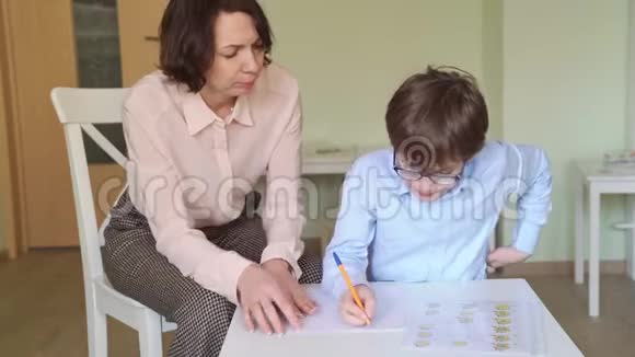 一个和老师在一起的男孩在桌上的灯光下接受沙疗视频的预览图