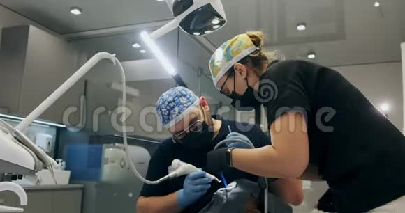 牙医在办公室工作两个牙医做空气流动牙齿清洁视频的预览图
