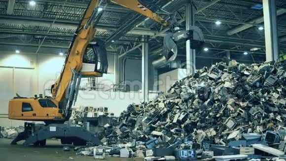 挖掘机正在从一堆垃圾中抓取碎片回收行业废旧电子回收工厂视频的预览图