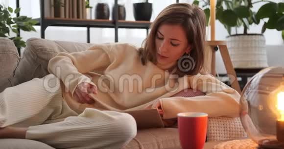 女人一边喝咖啡一边在沙发上看书视频的预览图