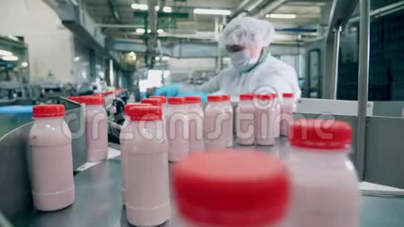 工厂工人从移动线路上挑选酸奶瓶视频的预览图