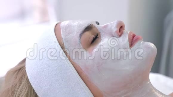 女性躺在水疗沙龙的肖像脸上戴白色面具侧视视频的预览图