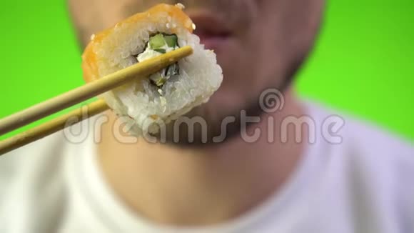在色键背景上有刚毛的雄性嘴的特写一个人吃寿司日本菜用筷子卷视频的预览图