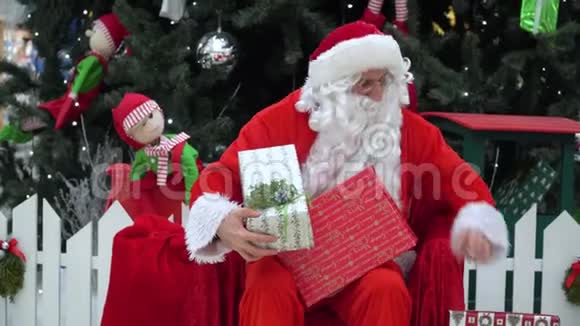 圣诞老人把礼物放在商场的一个袋子里圣诞老人对着镜头打手势视频的预览图