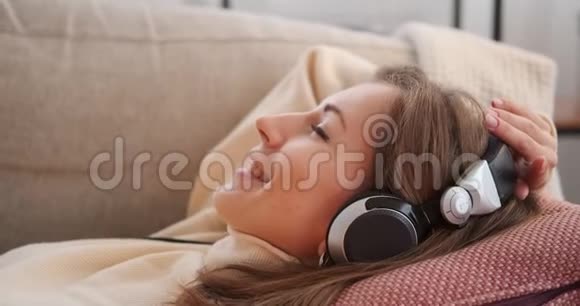 女人在沙发上用耳机听歌视频的预览图