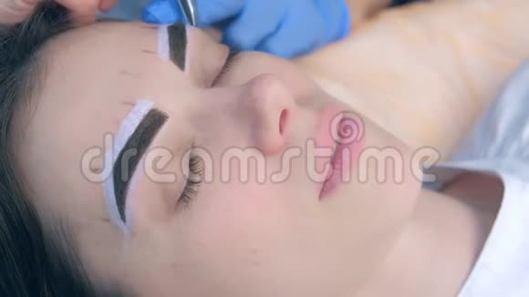 美容师用镊子夹着眉毛对着美容院的女人脸视频的预览图