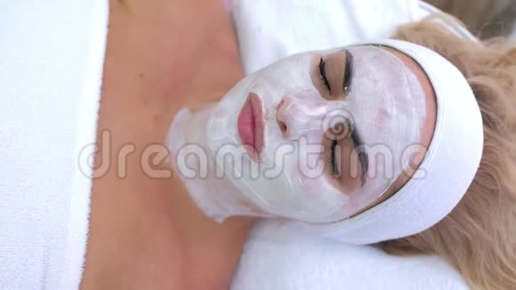 女性躺在水疗沙龙的肖像脸上戴白色面具俯视视频的预览图