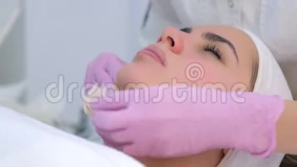 美容师戴手套从女人脸上擦拭护肤面具特写肖像视频的预览图