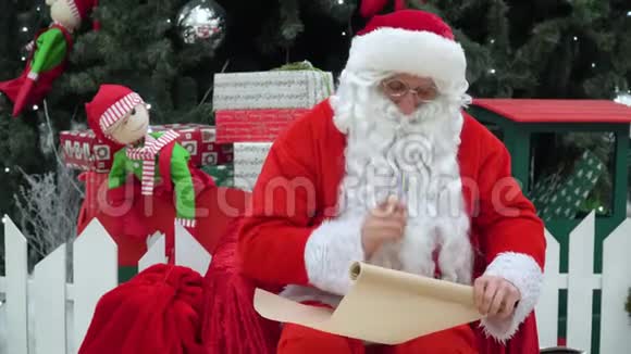 圣诞老人坐在商场上手里拿着一袋礼物上面写着一些东西视频的预览图