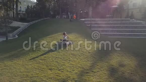 骑自行车的女人躺在公园的草地上用手机视频的预览图