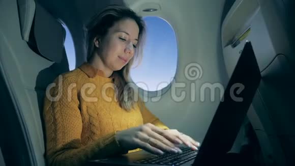 飞机上的一位女士正在笔记本电脑上打字微笑着视频的预览图